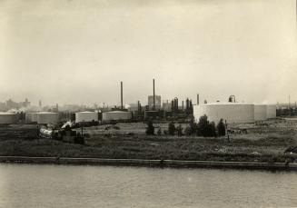 Image shows oil storage tanks by the lake.