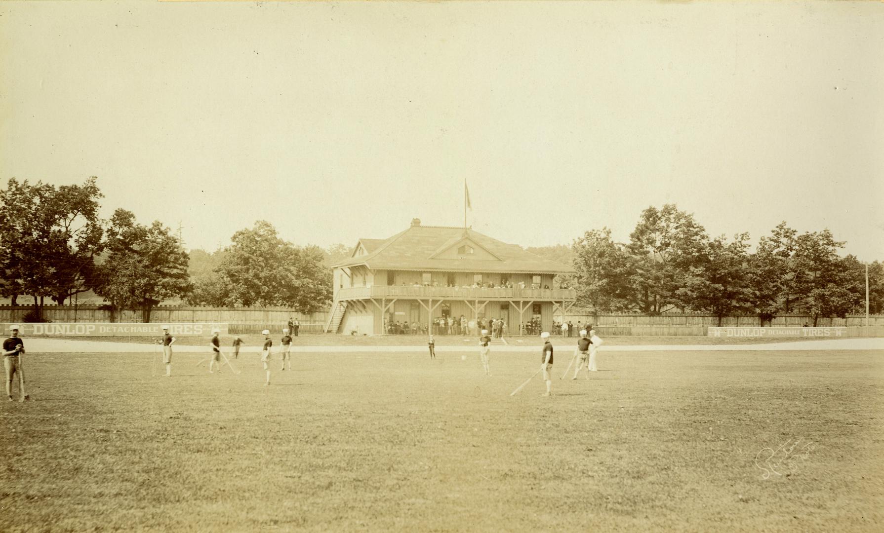 Image shows a club members on the lawn playing. There is a club building in the background.