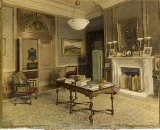 Image shows an writing room with a desk in the centre and a chair on the left. There are a numb ...