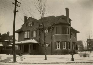 Image shows a three storey residential house along the street in winter.
