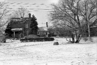 Image shows a house with a few trees on the sides in winter.