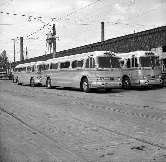 Image shows three buses that are parked by the building.