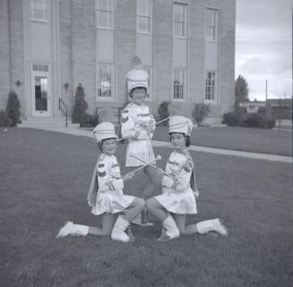 Image shows three parade participants posing for a photo on the lawn.