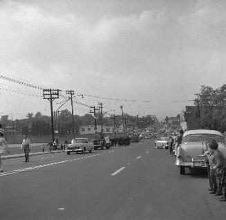 Image shows a street view and parade participants.