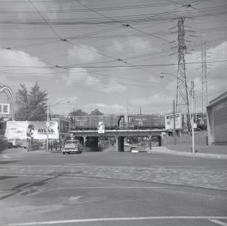 Image shows a street view at the intersection with a CP rail bridge in the background.