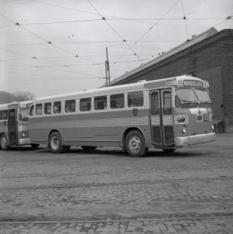 Image shows a few buses parked by the building. 