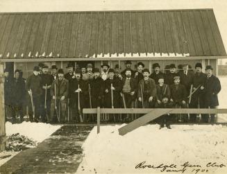 Image shows a group of people posing for a photo by the building in winter.