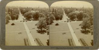 A photograph, taken from a higher vantage point, of a park with grassy lawns, flower gardens, t ...