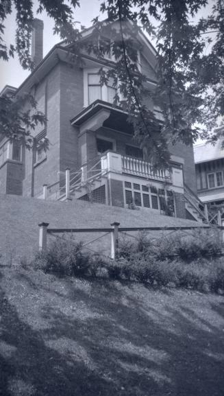 Image shows a very limited view of a two storey residential house on a hill.