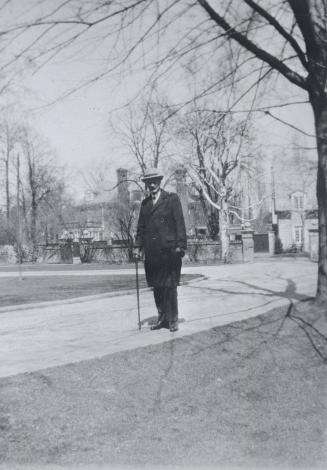 Image shows a gentleman walking along the road with some houses in the background.