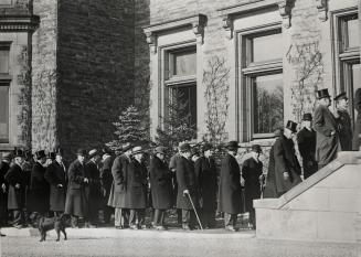 Image shows a number of people outside the building walking towards the entrance.