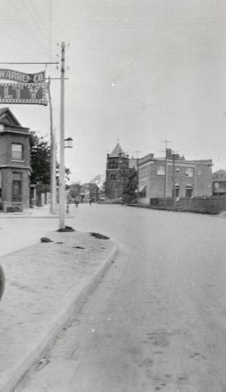 Image shows a street view with some houses on both sides.
