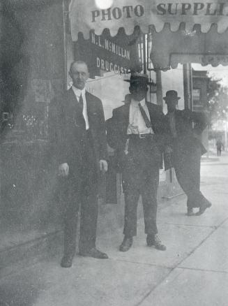Image show three gentlemen standing in front of the drug store.