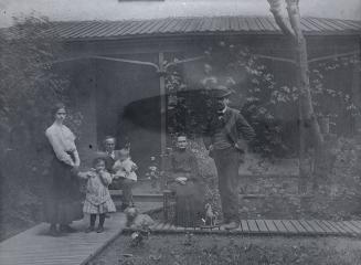 Image shows four adults and two children posing for a photo outside the house.
