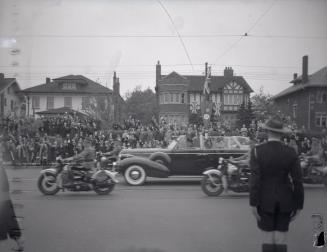 Image shows people in the street waving to the King as he passes by in the car.