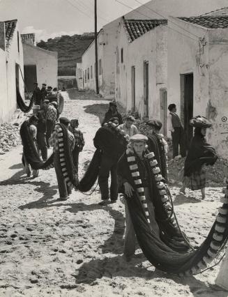 Portuguese fishermen carry nets through the village of Nazare, 1954