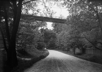 Image shows a road view with a bridge over it.
