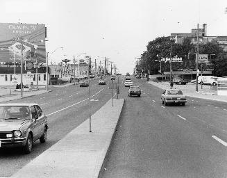 Image shows a street view with a number of cars passing.