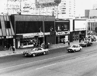 Yonge-Eglinton Intersection, east side of Yonge. Image shows mostly Yonge street and a few cars ...