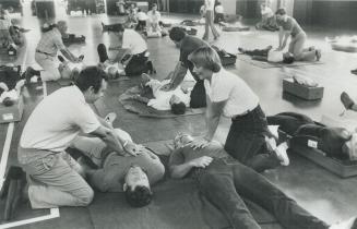 Photo of CPR rescue class. Many people are delivering CPR on a partner laying on the floor.