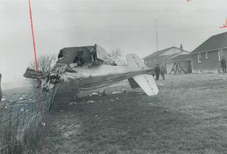 Crumpled wreckage of twin-engined Piper Apache, in which four men died early today, lies tilted over fence in backyard on Cattrick St., in Malton, qua(...)