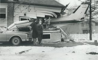 The tail of a twin-engined Cessna plane sticks out of the wrecked Oshawa house of Earl Moore and his wife, Verna, while Police Constable Dave Fitzgera(...)