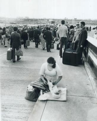 A mother changes her 3-month-old son s diapers while waiting to get back into Terminal 2, along with hundreds of other travellers and employees of Air(...)