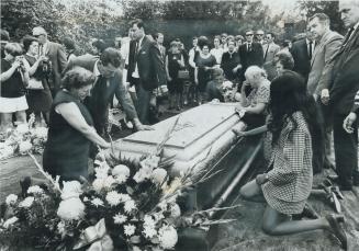 Relatives of the dead kneel and touch one of the five symbolic coffins at a graveside service of Mount Pleasant Cemetery yesterday. This was one of fi(...)