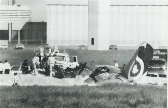 Airport firefighters pour chemical foam on wreckage of twin-engined cargo plane that crashed at Malton airport today, killing the two-man crew
