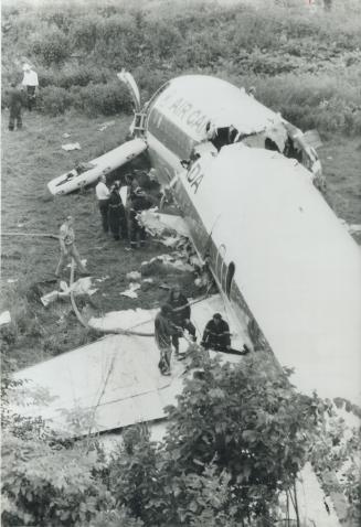 Firemen attempt to drain fuel from wing tank of the twisted broken airliner