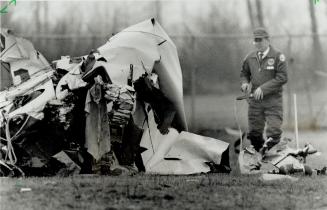 An investigator examines the wreckage of a two-engined Piper Twin Comanche today, seeking the cause of the crash at Toronto Island Airport