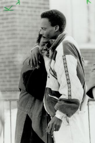Comforting arms: An unidentified man comforts the distraught mother of one of the babies outside the apartment building on Lawrence Ave