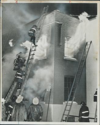 Hot foot on high. Flames bursting from the window of a Wellington St. W. plant hasten the steps of a fireman climbing to the roof to battle the three-(...)
