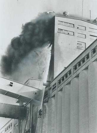 Firemen reach for the sky yesterday to battle a fire atop the Maple Leaf Mills giant waterfront grain elevators