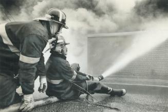 Sitting down on the job. Fireman had to keep low to avoid the thick, acrid smoke from a blaze in the parts warehouse of a Mississauga auto company yes(...)