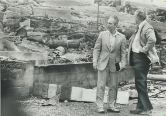 Natural resources minister Rene Brunelle (left) and Northern Affairs Minister Leo Bernier tramp through the ruins of Cobalt, devastated by $4 million (...)
