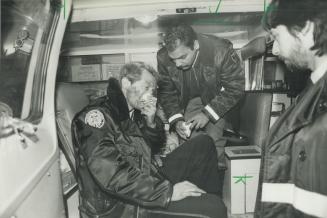 A Metro policeman gulps oxygen as an ambulance attendant helps him