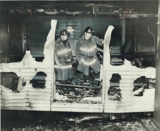 Burned-out ruins of four Bloor subways cars are examined by firefighters at Christie subway station