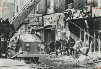 Messy job: Firefighters clean up debris yesterday following early-morning three-alarm blaze in Woolworth's store