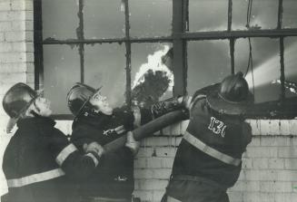Firemen struggle with a hose as they fight a stubborn fire that burned for hours in an abandoned East York factory on Wednesday