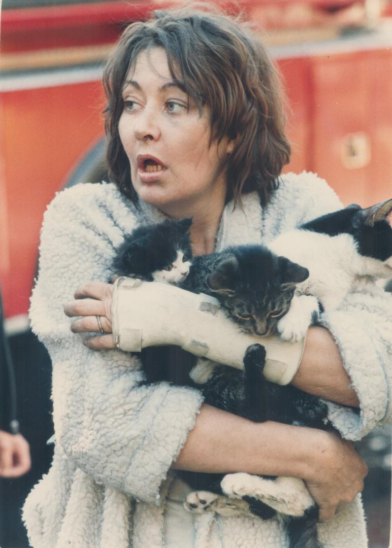 Shari Thompson cradles three of her six kittens as she stands outside a burning rooming house on Melbourne Ave