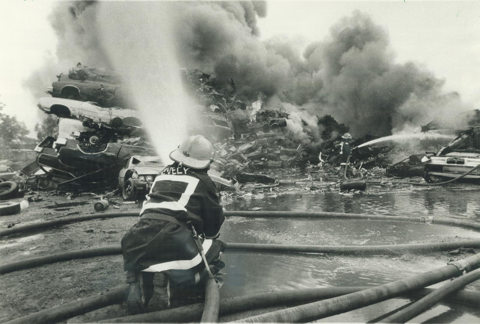 Wrecking yard catches fire. Firemen turn their nozzles on a 30-metre (100-foot) pile of tires that caught fire yesterday and sent up a large plume of (...)