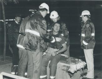 Perilous work: Firefighter John DiFrancesco is treated by paramedics after 90 kilograms (200 pounds) of bricks fell on his head from blazing hotel yesterday