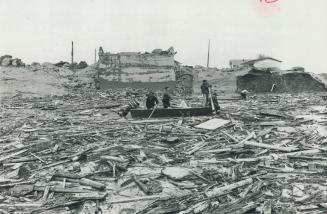 Rescuers pilot a boat through debris as the search continues for those missing