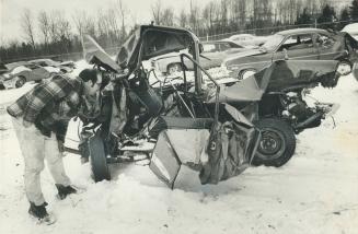 One of the smashed cars from the Highway 400 accident is examined near the site of the crash