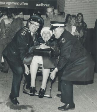Second tirp: Seventy-five-year-old Isabella Donohue takes it all in good spirits as she is carried from Sherway Gardens by ambulance men on her second evacuation trip yesterday
