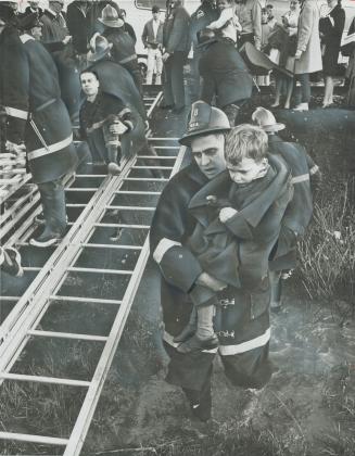 Rescued from sabotaged train, a shocked youngster huddles in arms of Etobicoke fireman James Grant as he is carried from the scene of the derailment i(...)