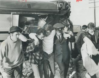 An injured passenger is helped away from wreckage of derailed train yesterday by a policeman and civilian About 30 passengers were injured when six pa(...)