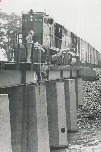 Last-second leap as a freight train roars down is the object of boys aged 10 to 15 who play a deadly game of chicken on a trestle 25 feet above a rese(...)