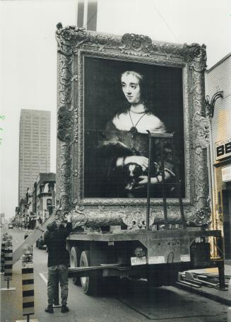 Tall order. Workers hoist and hang a reproduction of Rembrandt's Lady Petting Lap Dog on a building near Yonge and Bloor Sts. yesterday. The replica p(...)